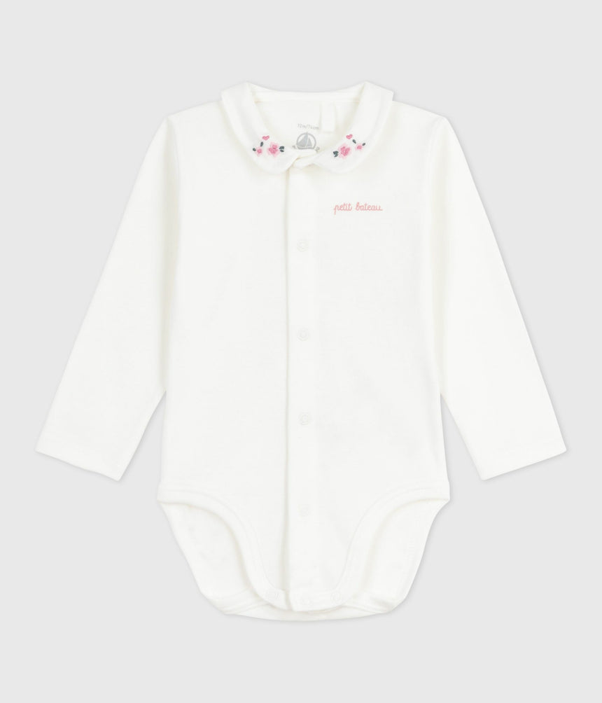 babies body with an embroidered collar and a message on the chest