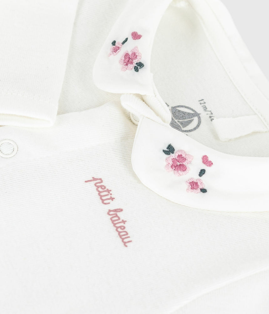 babies body with an embroidered collar and a message on the chest
